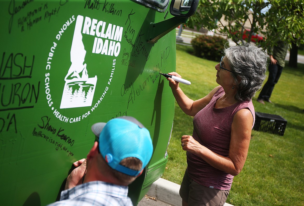 Roz Korczyk signs the Reclaim Idaho &#147;Medicaid Express&#148; bus Thursday afternoon at the Human Rights Institute. 

LOREN BENOIT/Press