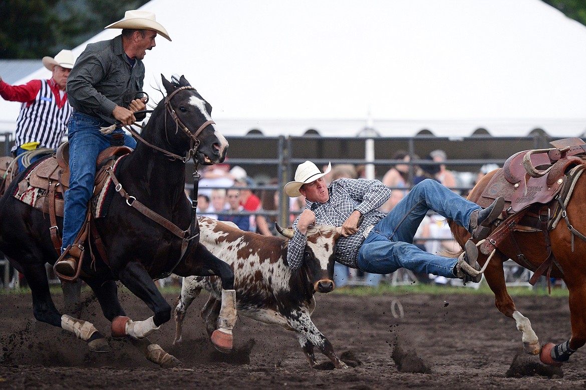 Hank Hollenbeck, right, of Molt, competes during the Steer Wrestling event at the Bigfork Summer Pro Rodeo on Friday. (Casey Kreider/Daily Inter Lake)