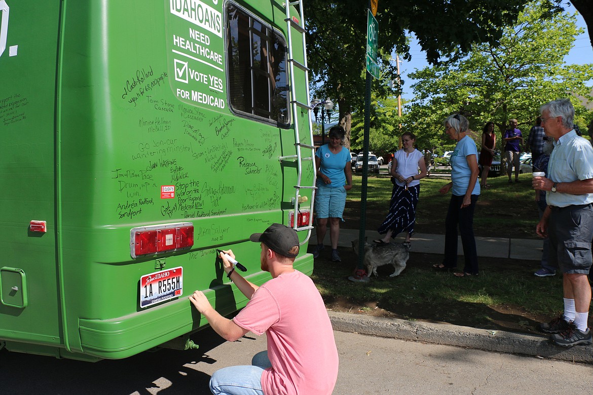 (Photo by CAROLINE LOBSINGER)
Daniel Radford signs the Medicaid expansion bus Thursday morning shortly before Reclaim Idaho&#146;s Luke Mayville began the drive to Boise to deliver signatures to the Idaho Secretary of State for verification.