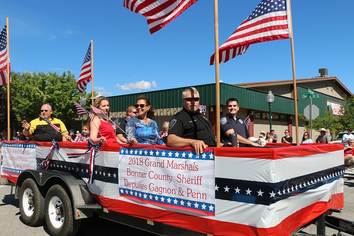 (Photo by CAROLINE LOBSINGER)
Sandpoint Police officers Mike Hutter, far left, and Eric Clark, far right, and Bonner County Sheriff&#146;s Deputies Mike Gagnon, center, and Justin Penn, pictured to Gagnon&#146;s right, and their families take part in the Sandpoint Lions&#146; Grand Parade on the Fourth of July on Wednesday. The four were named grand marshals of the parade by the Sandpoint Lions in recognition of their service to the community.