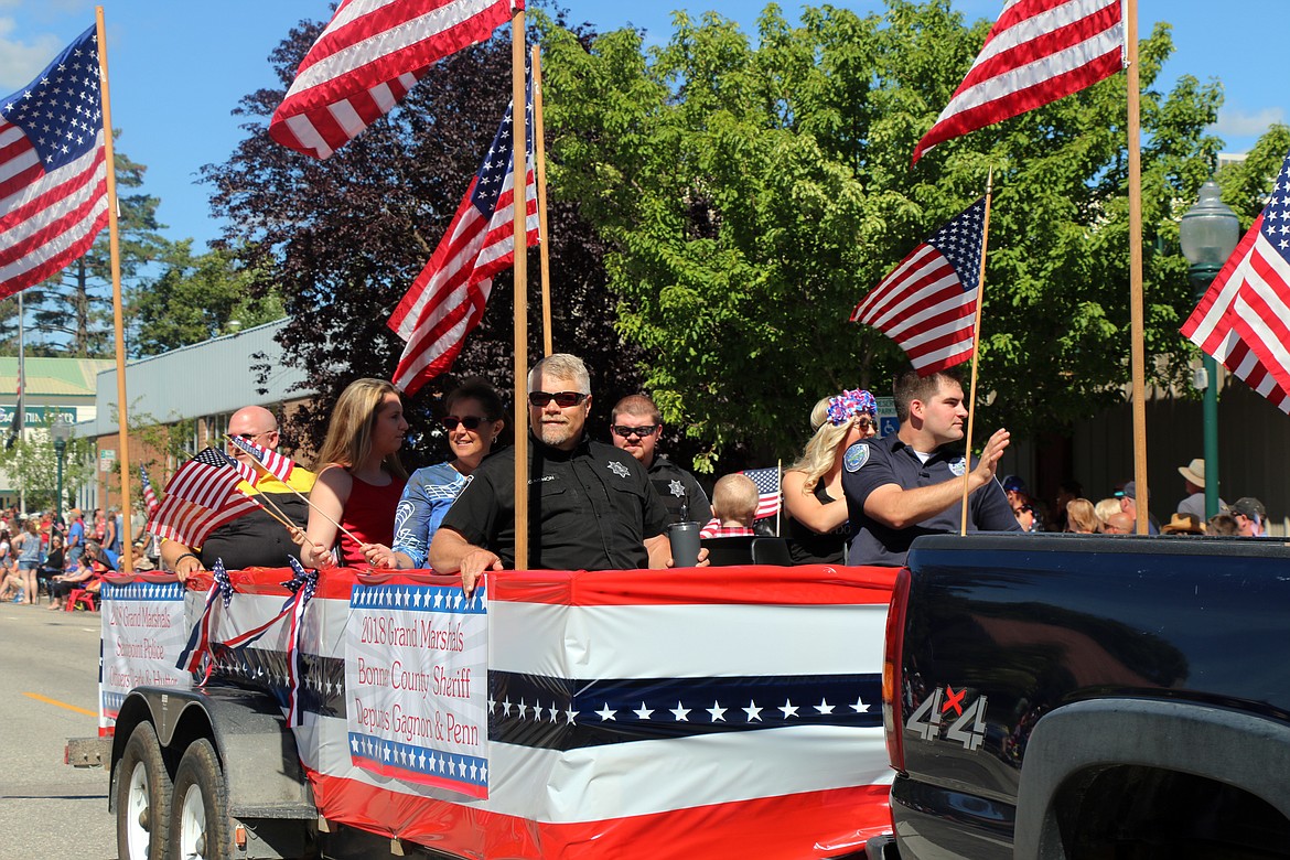 (Photo by CAROLINE LOBSINGER)Sandpoint Police officers Mike Hutter, far left, and Eric Clark, far right, and Bonner County Sheriff's Deputies Mike Gagnon, center, and Justin Penn, pictured to Gagnon's right, and their famlies take part in the Sandpoint Lions' Grand Parade on the Fourth of July on Wednesday. The four were named grand marshals of the parade by the Sandpoint Lions in recognition of their service to the community.