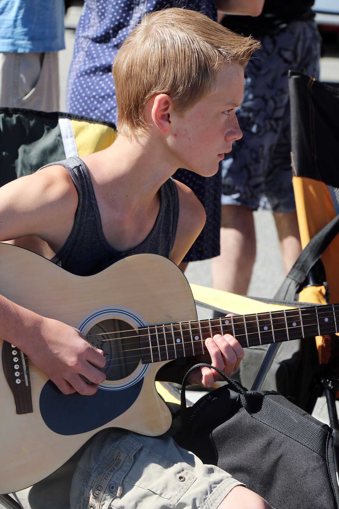 (Photo by CAROLINE LOBSINGER)Caedmon Leister plays the guitar as he waits for the start of the Sandpoint Lions' Grand Parade on the Fourth of July on Wednesday.