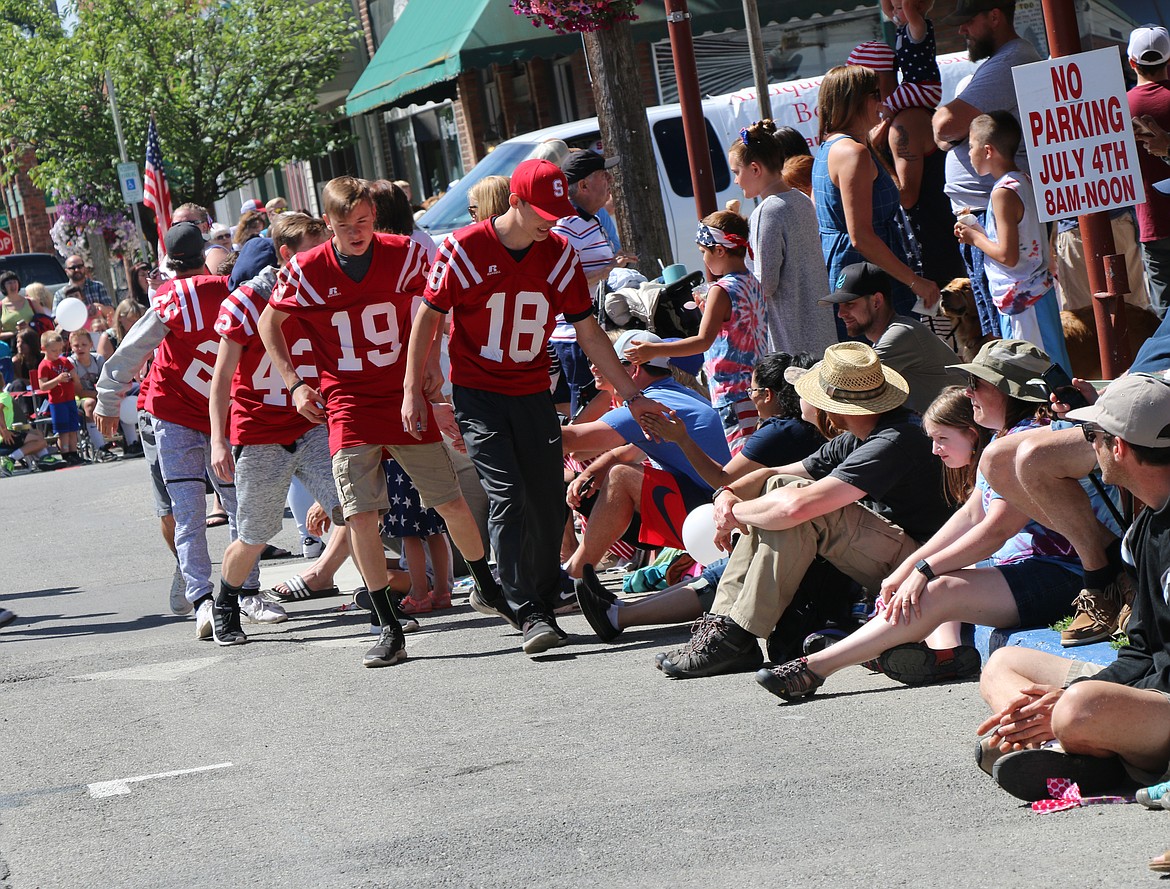 (Photo by CAROLINE LOBSINGER)Sandpoint High School football team members give high fives to the crowd as they take part in the Sandpoint Lions' Grand Parade on the Fourth of July on Wednesday.