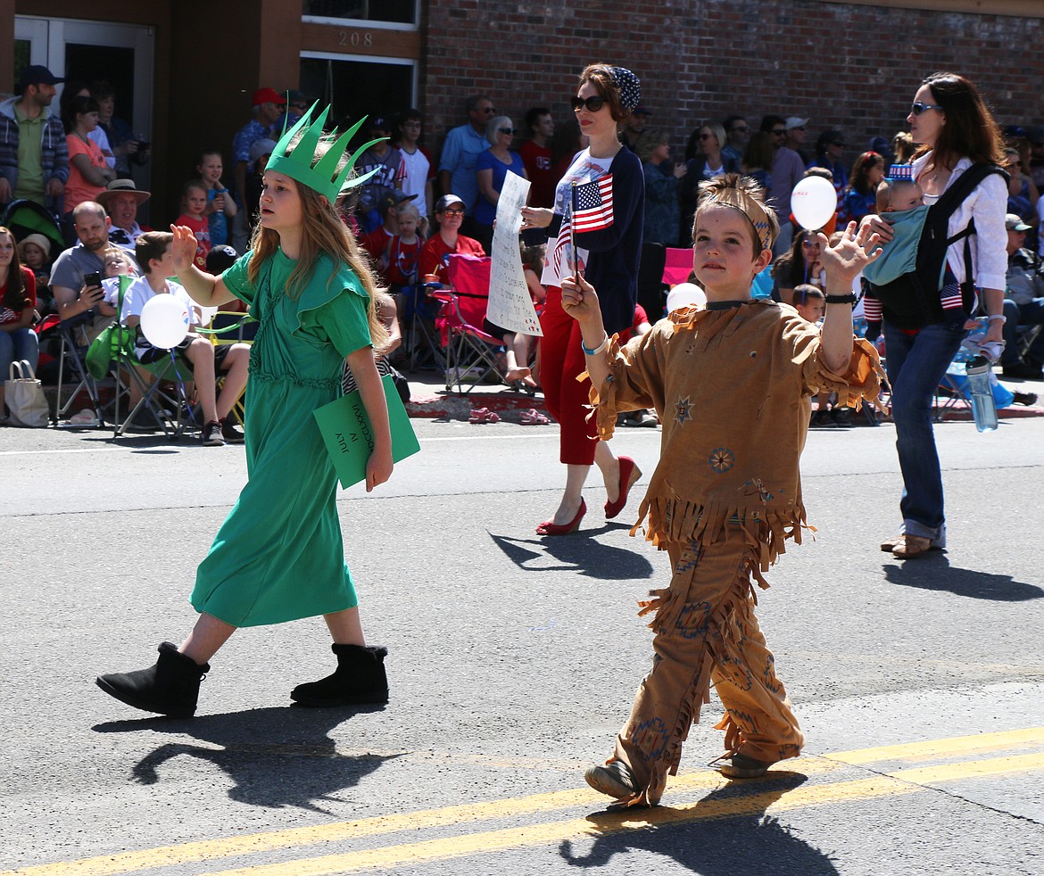 (Photo by CAROLINE LOBSINGER)A pair of parade participants wave to the crowd as they take part in the Sandpoint Lions' Grand Parade on the Fourth of July on Wednesday.