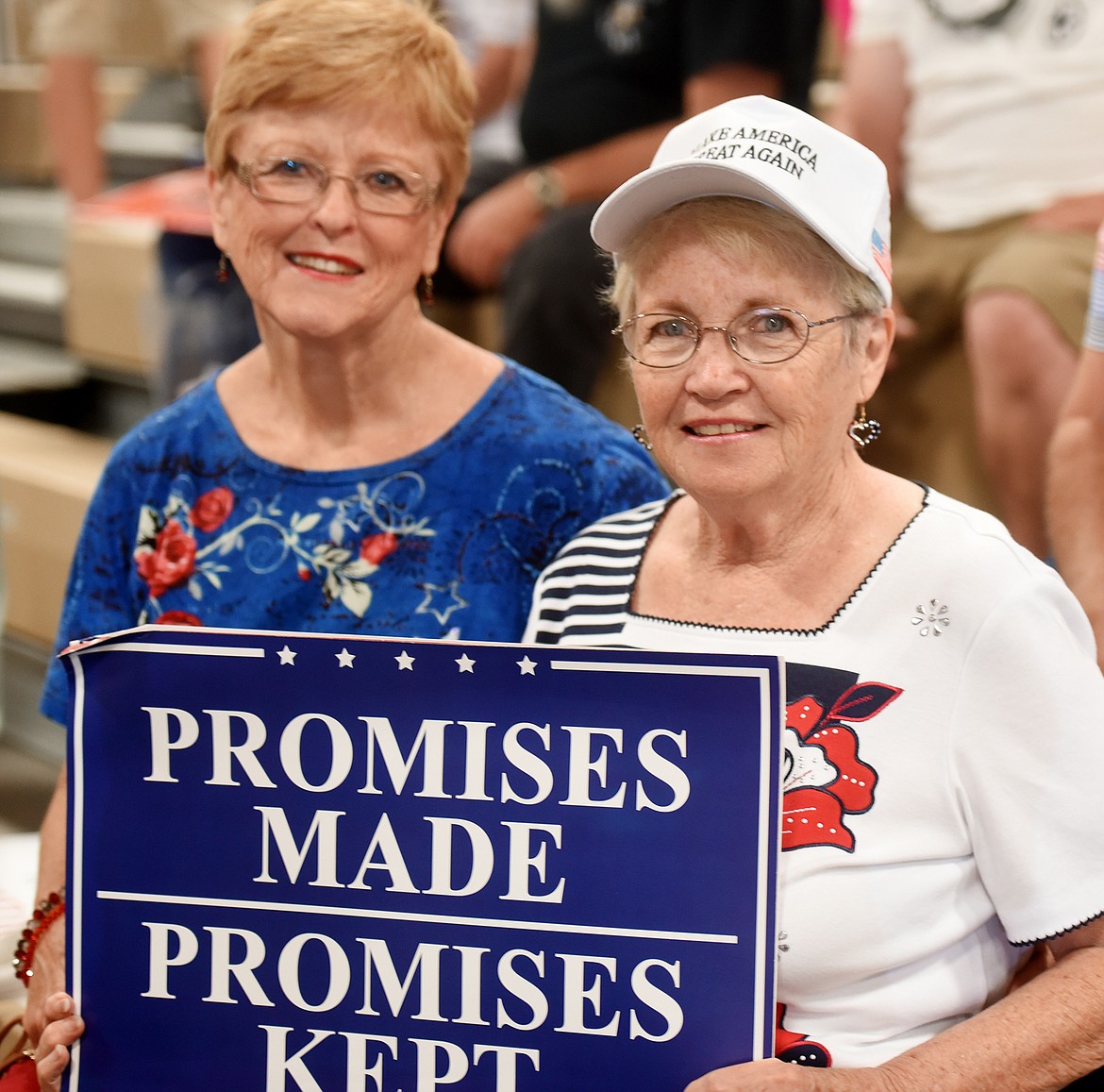 Judy Hogan, right, of Kalispell, holds a sign and sits with her friend at the start of the rally.