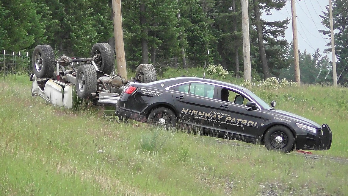 A Ford F-250 pickup truck rests on its roof after it wrecked Tuesday afternoon on Highway 35 near Creston while Montana Highway Patrol Trooper David Mills works on the accident report. The driver of the truck was testing its brakes for the Bigfork July 4 parade when it rolled. The driver and passenger were conscious when they were transported from the scene. (Scott Shindledecker/Daily Inter Lake)