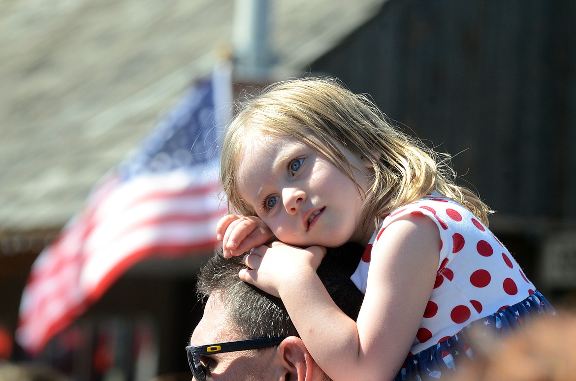 A child finds a perch to watch the stream of floats.