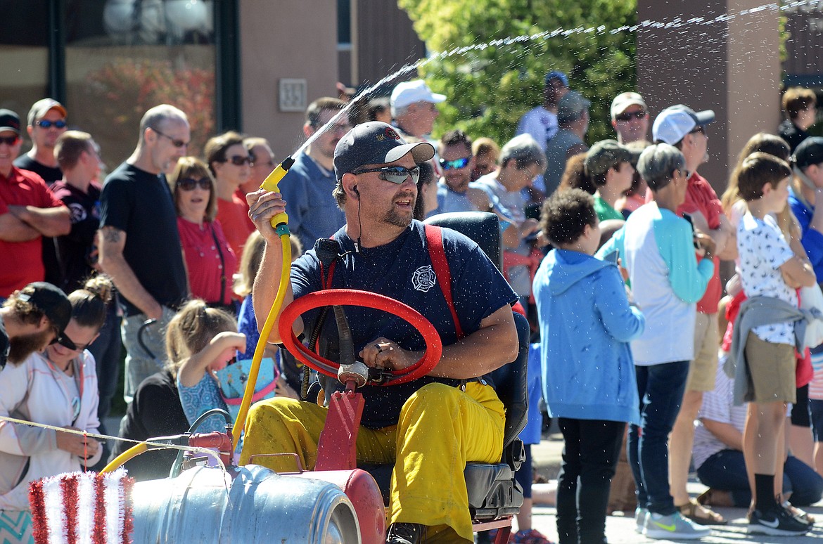 A South Kalispell firefighter sprays water on spectators lining Main Street in downtown Kalispell to watch the annual Fourth of July parade Wednesday morning. This year&#146;s theme was &#147;Funky Fourth.&#148; More than 80 entries participated in the long line of floats. (Matt Baldwin photos/Daily Inter Lake)