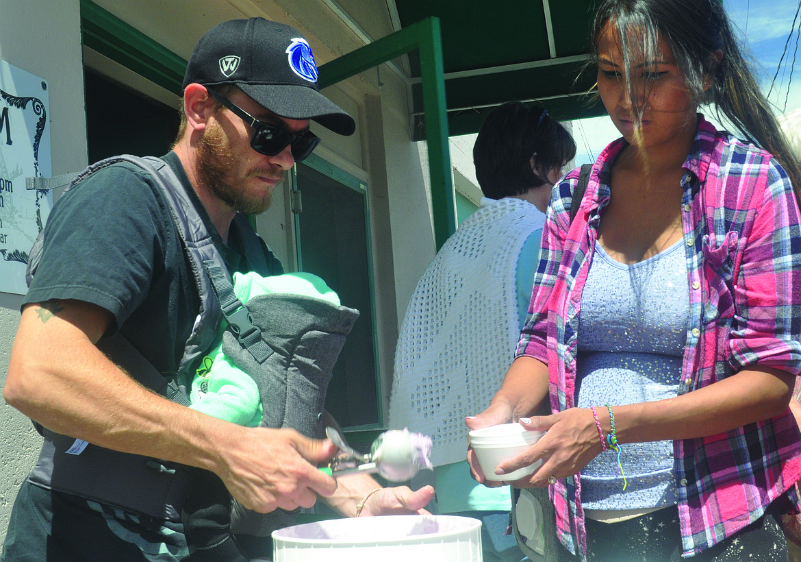 NICK HUMPHRIES does double duty, scooping huckleberry ice cream during the Fourth of July social hosted by the Polson Flathead Historical Museum. Humphries prepares to fill a bowl held by Alexis Scott. The couple lives in Pablo.