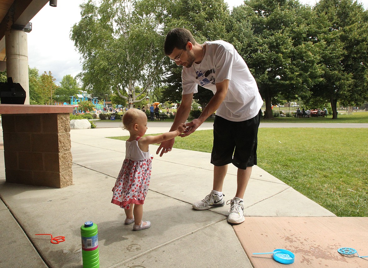 Matthew Palm of Coeur d'Alene exchanges bottles of bubbles with his 19-month-old daughter, Trinity, during a reunion for Kootenai Health's Neonatal Intensive Care Unit (NICU) families Saturday in McEuen Park. Trinity weighed a little more than 2 pounds when she was born three months early. She spent 75 days in Kootenai Health before being released, just shy of two weeks before her original due date. She is now flourishing and quite captivated by bubble machines. (DEVIN WEEKS/Press)