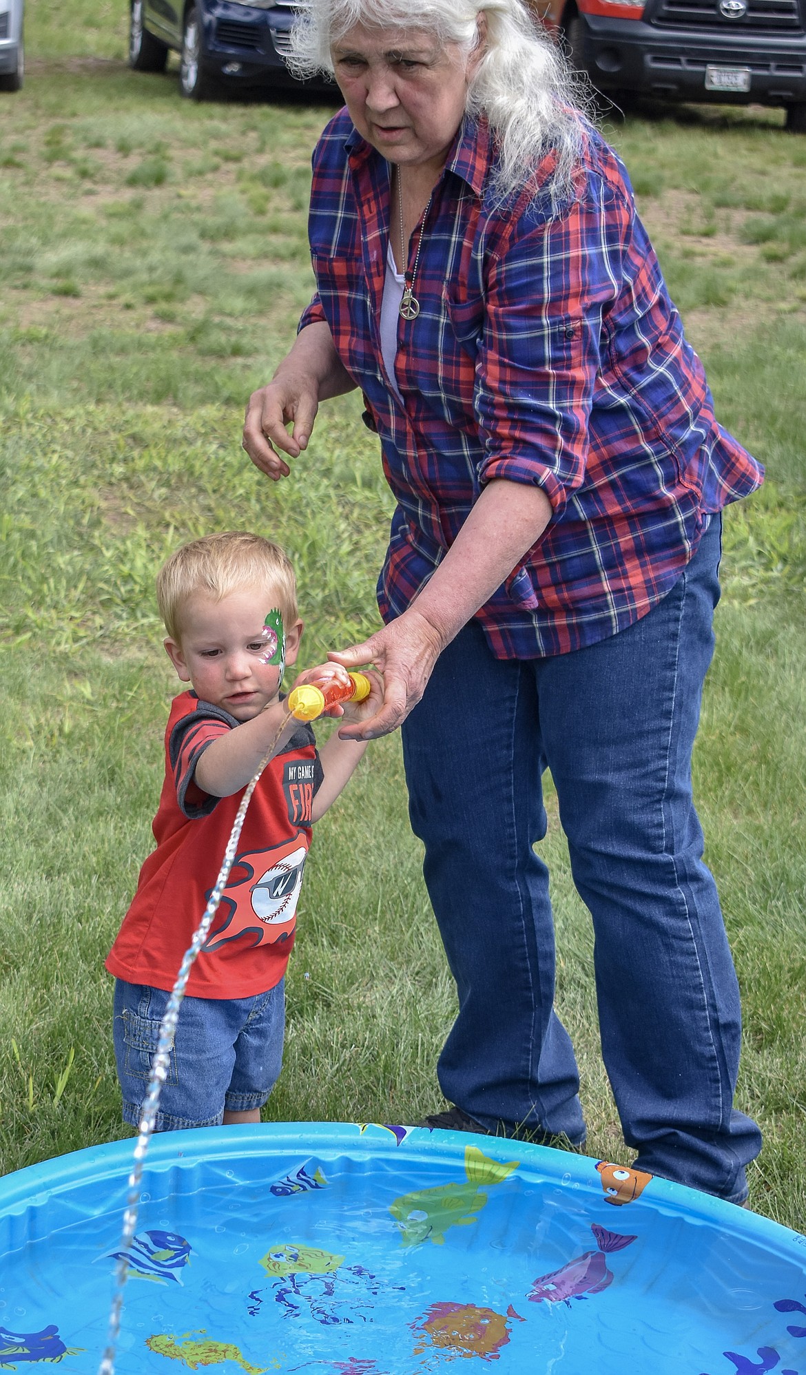 Community volunteer Bonnie Surrell helps Laramy Allen get a handle on a water squirter used for one of the childrens&#146; games during the sixth annual Yaak School Arts and Crafts Fair Saturday, June 30. 
(Ben Kibbey/The Western News)