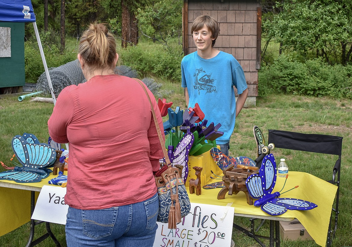 Recent eighth grade graduate Jaden Holly talks with a visitor at the table where Yaak School students&#146; artwork was for sale to help raise money for the school, during the sixth annual Yaak School Arts and Crafts Fair Saturday, June 30. 
(Ben Kibbey/The Western News)