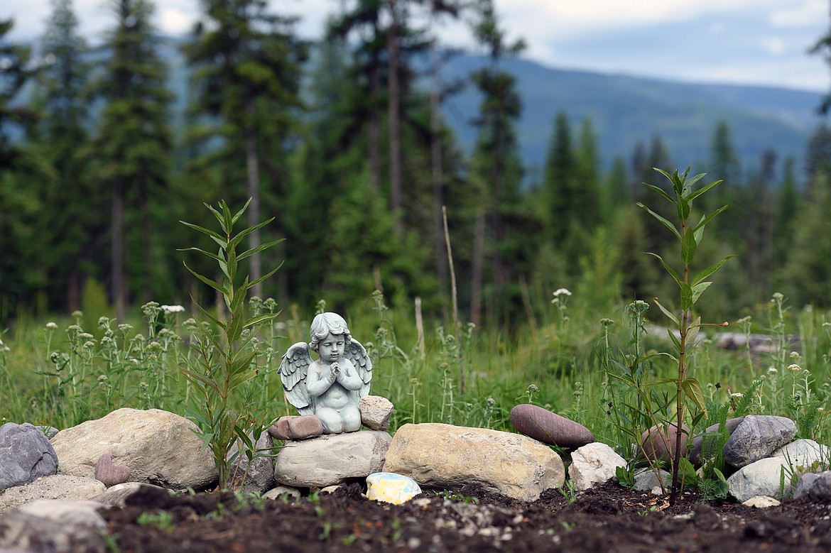 A small statue stands along the edge of a grave site.