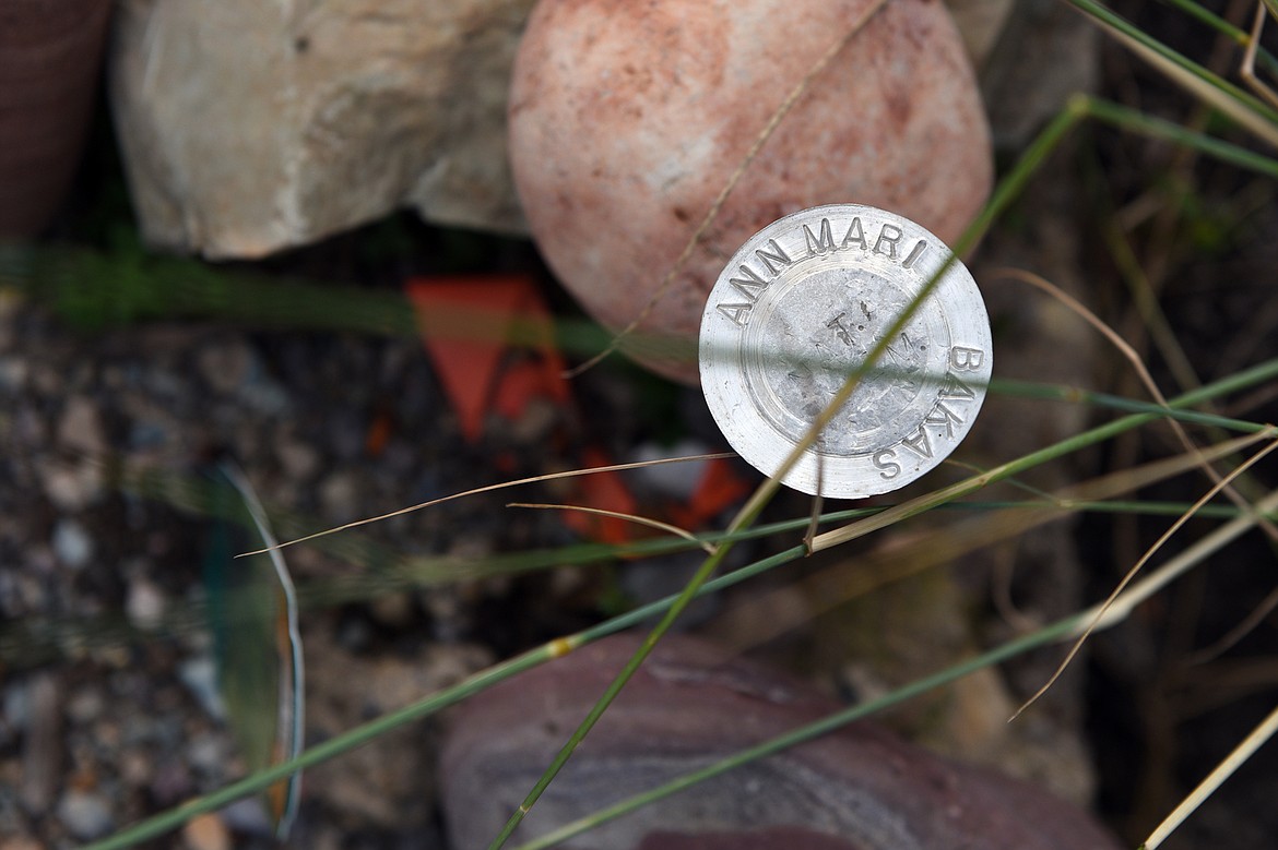 A simple silver marker at the corner of a grave site.