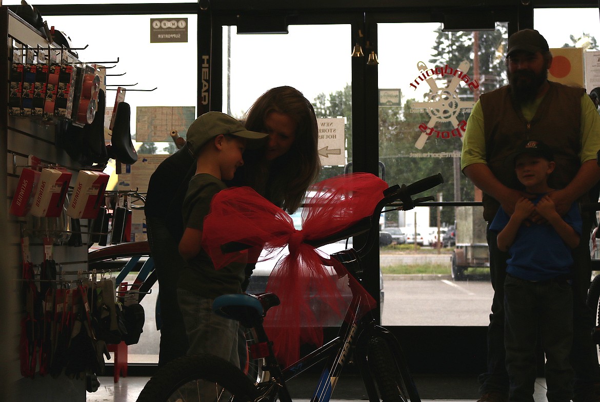 (Photo by MARY MALONE)
Local 7-year-old Easton McNall couldn&#146;t hide his smile on Thursday as he was the first recipient of a bike donated through a new program by Sandpoint Sports owners Lisa Campbell and Svein Nostdahl. Campbell is making earrings out of bicycle tire tubes and selling them to purchase a new bikes for deserving children in the community. Easton is pictured on the left with his mother, Amanda McNall, with his brother Holt and father Dan McNall on the right.