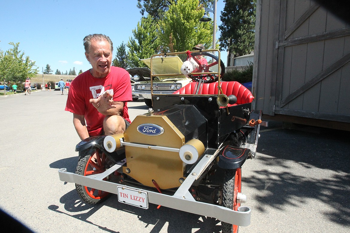 Robert Sadler of Kingston crouches next to his 1950 Ford Model T Lizzy Torpedo during the Post Falls Festival car show Saturday. &quot;Tin Lizzy&quot; is a quarter-scale of a regular Model T and took Sadler about 18 months and $3,000 to complete. &quot;My favorite part is the front end because it's a Model T, and the lights are actually made out of fruit cans,&quot; he said. &quot;I built the bumper, I fabricated and welded it and I built the windshield, built all that by hand.&quot; (DEVIN WEEKS/Press)