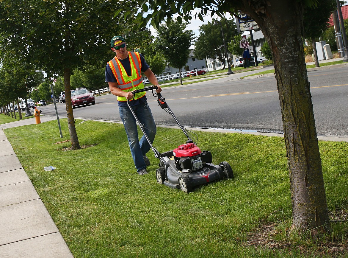 Hayden Parks employee Cody Hensley mows a section of grass along Government Way on Tuesday in Hayden. (LOREN BENOIT/Press)