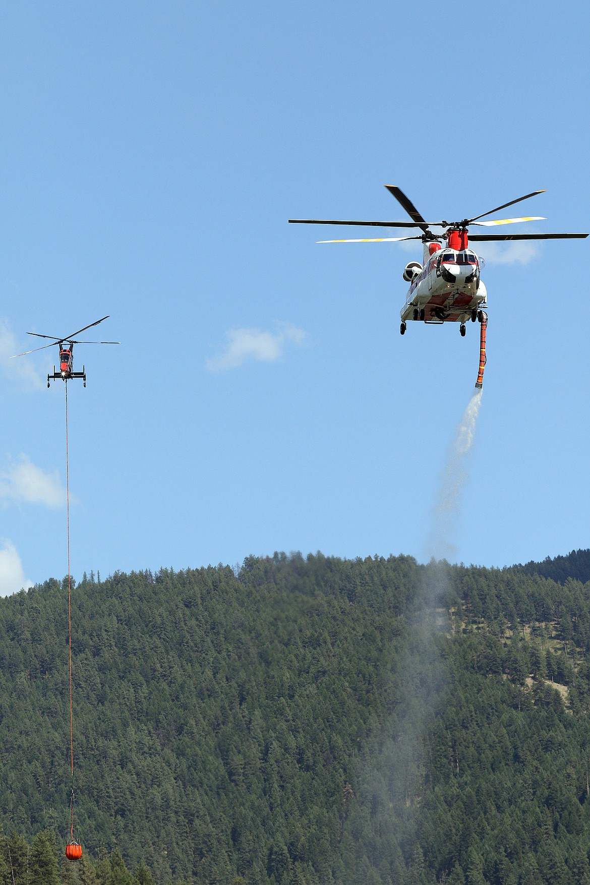 The first two helicopters assigned to a wildfire north of Libby draw water from the Kootenai River Thursday evening. (John Blodgett/The Western News)