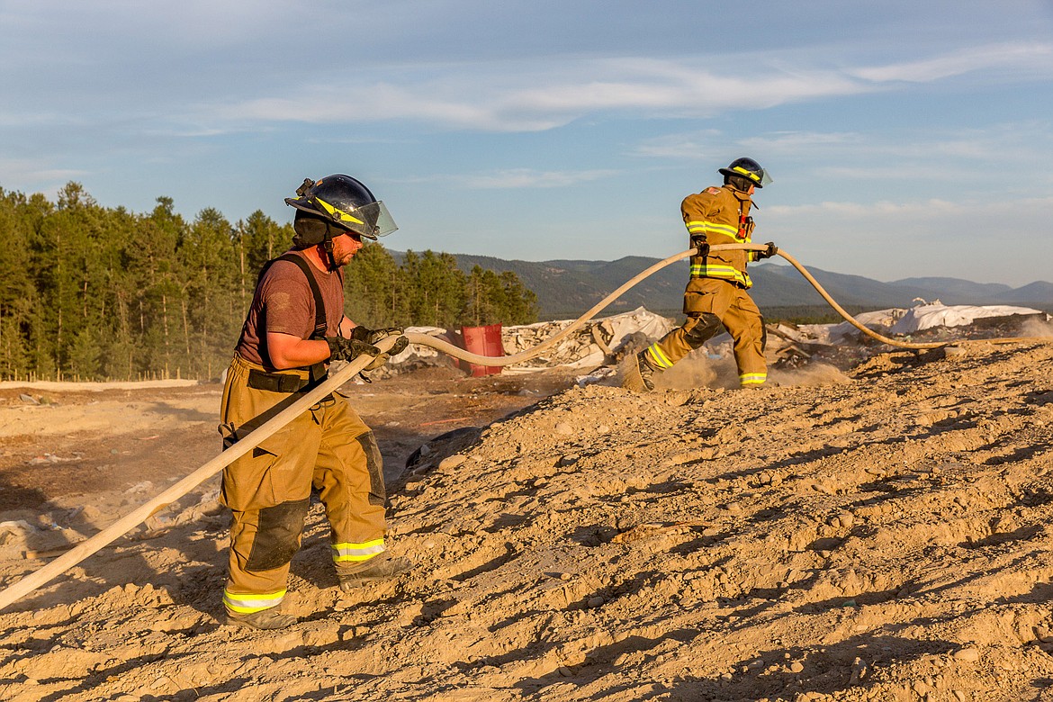 Libby volunteer firefighters Zach Weed, left, and Bryan Thompson work a fire at the Lincoln County Landfill Friday evening, July 13. (John Blodgett/The Western News)