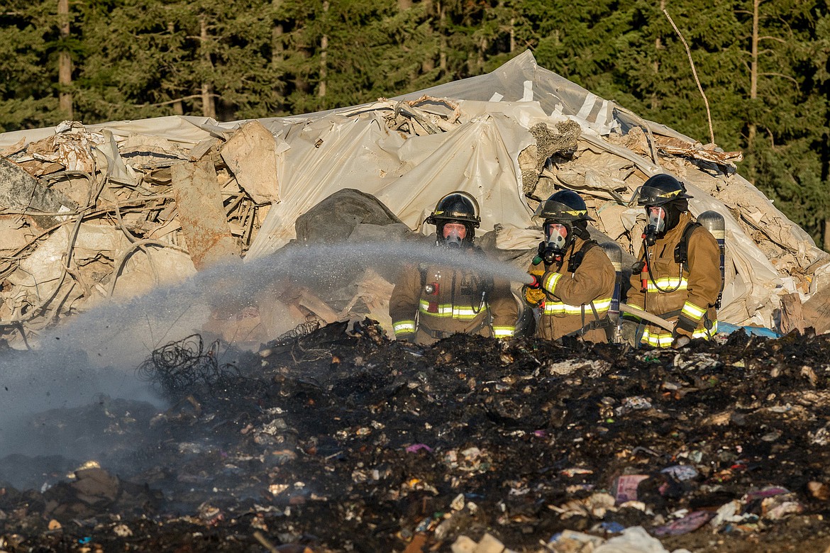 Libby volunteer firefighters Neil Benson, Brian Hobday and Brent Wood work a fire at the landfill Friday evening. (John Blodgett/The Western News)