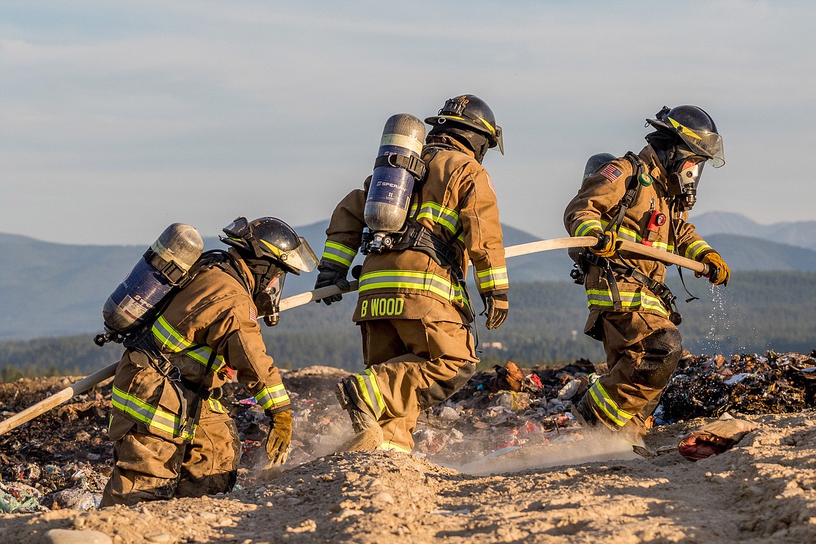 Neil Benson, Brent Wood and Brian Hobday move hose while working Friday night&#146;s fire at the Lincoln County Landfill. (John Blodgett/The Western News)