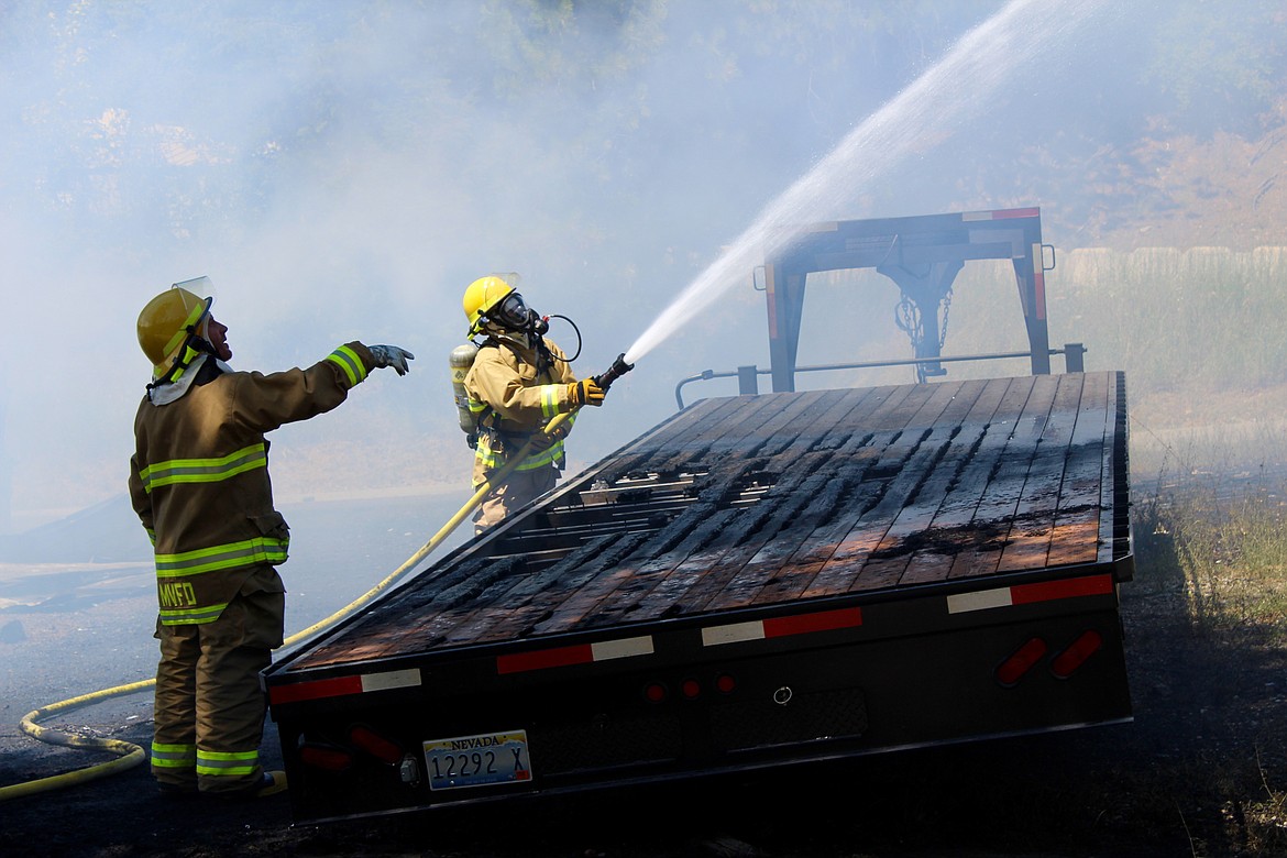 In addition to the trailers and wooden shack, the wind-fanned flames spread to a nearby flatbed trailer and a power pole. Firefighters spray the pole (not pictured) to keep the flames from moving up it.