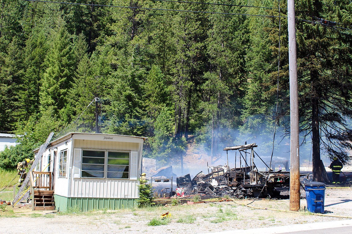 A wide shot of the affected area in Mullan. The destroyed living trailer and pop-up tent trailer can be seen on the right as crews attempt to salvage the living trailer on the left.