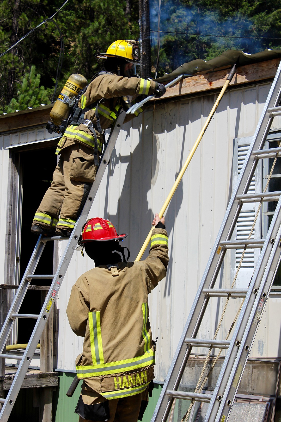 SCFD No.1 firefighters Daniel Kearney and Cyle Hanan pull on the roof of the second living trailer to access the fire that had spread to it.