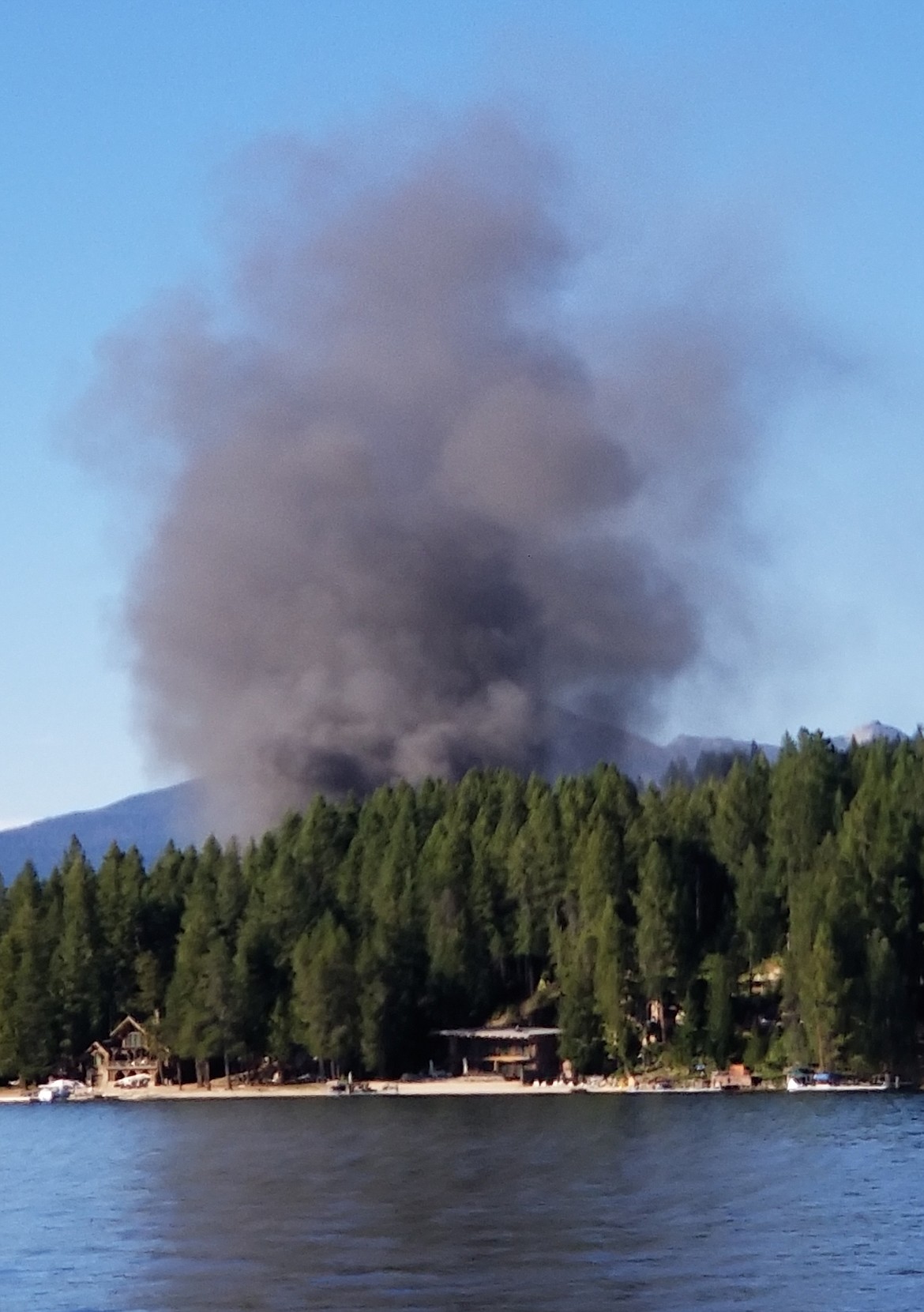 (Photo by BILL OLMO)
A column of smoke rises above the lake during a structure fire that reportedly claimed two cabins.