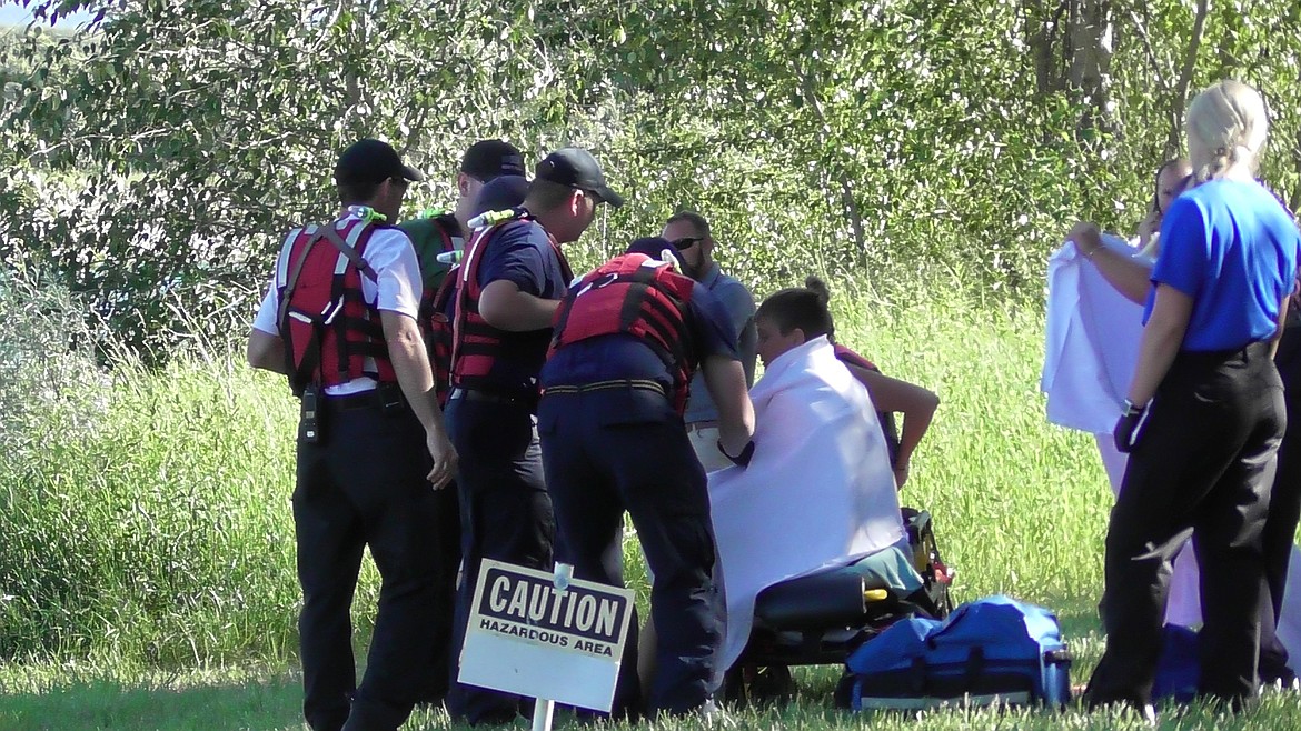 FIRST RESPONDERS tend to two kayakers after they were pulled from the Flathead River Tuesday evening. They were reportedly caught in a log jam upriver from the Spruce Park RV Park &amp; Campground. (Scott Shindledecker/Daily Inter Lake)