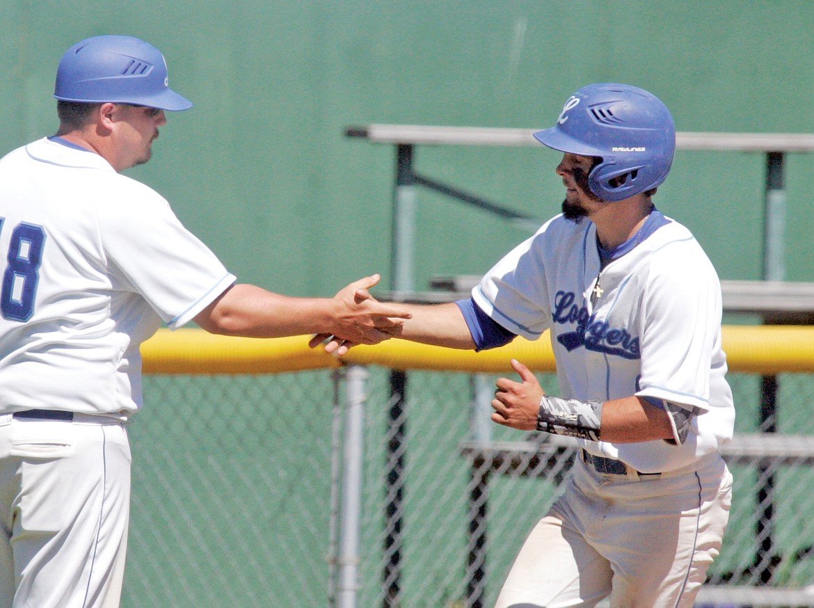 Tim Carvey shakes hands with third base coach Micah Germany as he heads for home on a two-RBI home run in the bottom of the third inning in the second game of a doubleheader vs. Cranbrook Saturday. (Paul Sievers/The Western News)