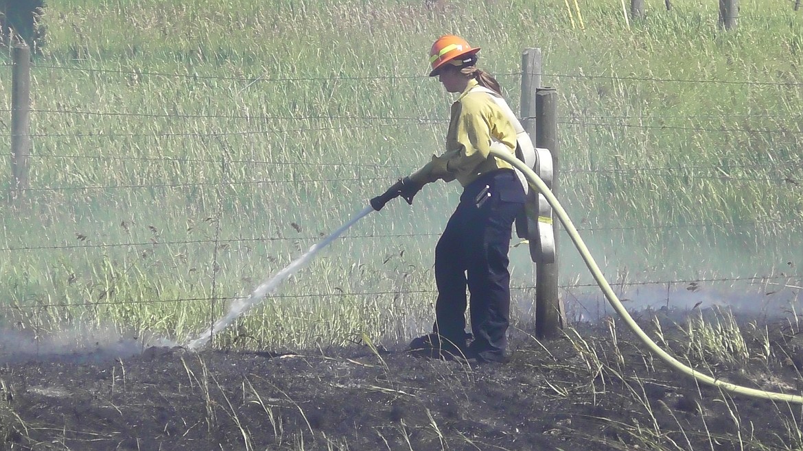 A SMITH Valley firefighter sprays water on a grass fire along the U.S. 93 bypass near the Foys Lake roundabout Tuesday afternoon. The fire was small, but strong winds gave first responders plenty of cause for concern. (Scott Shindledecker/Daily Inter Lake)