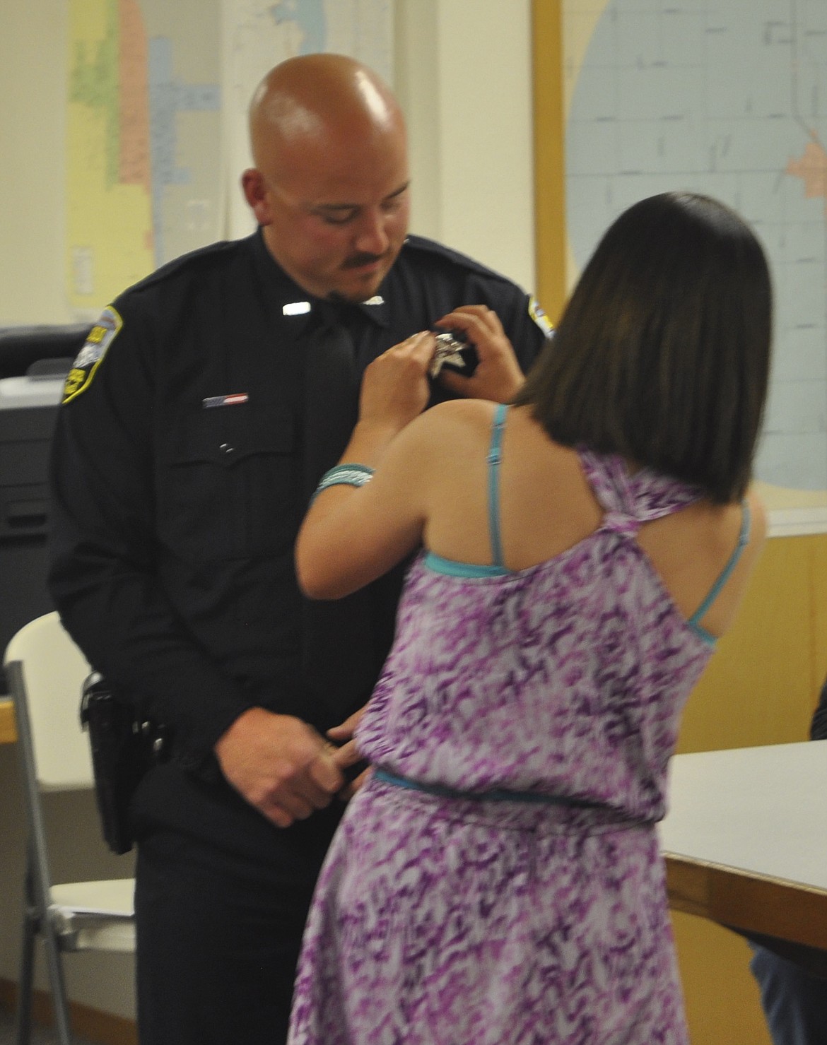 BRITTANY HORTIN pins a badge on her boyfriend, Corey White, who was re-hired by Ronan Police last week. (Ashley Fox/Lake County Leader)