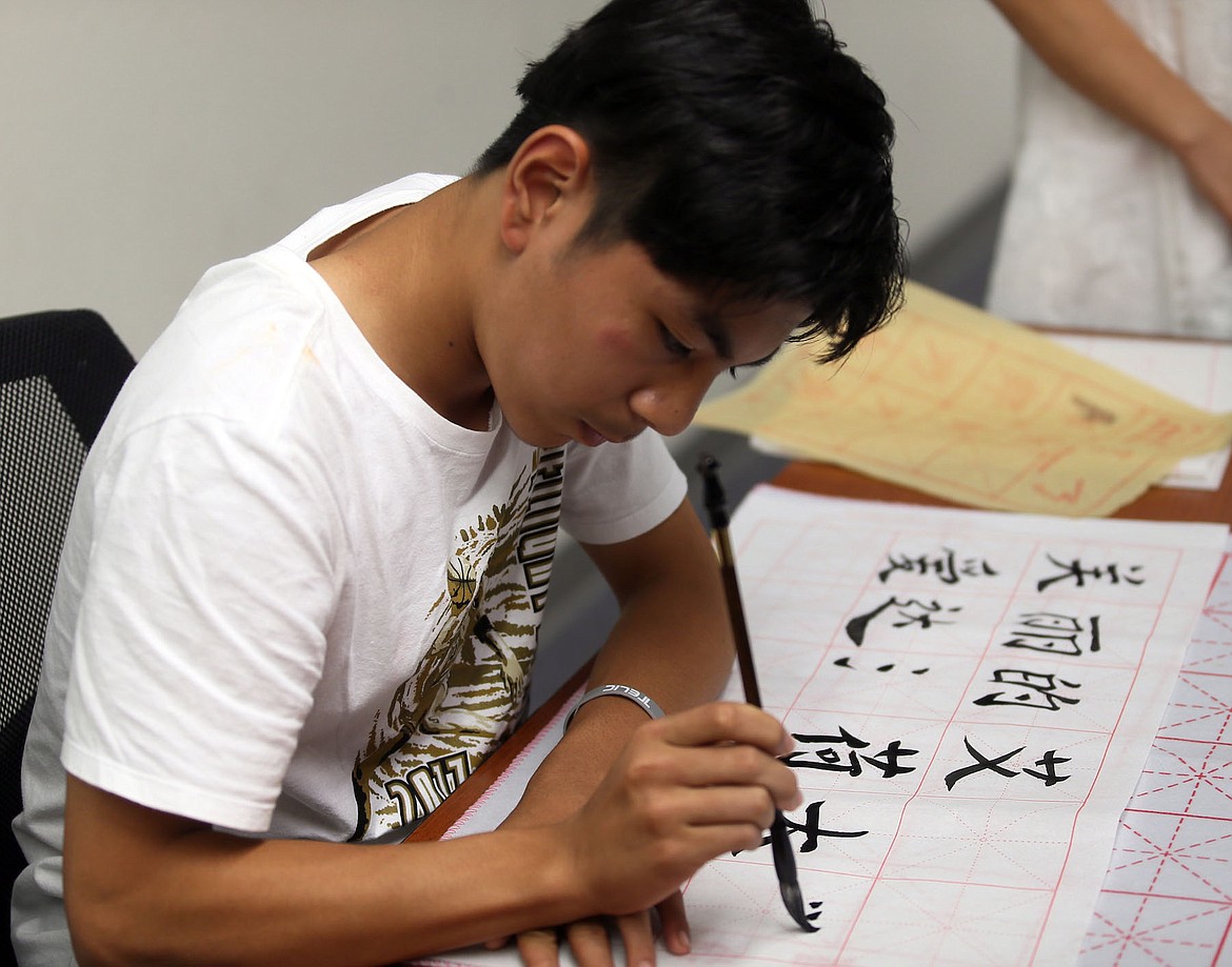 Jacky Sun writes the name of the University of Idaho in Chinese Thursday. The first character of the word &#147;Idaho&#148; in Chinese is &#147;love,&#148; said IDVenture founder Ying Xue. (JUDD WILSON/Press)