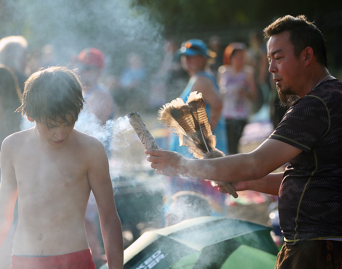 Judge William cleanses negative energy around Ashton Loken by the art of smudging with sage and feathers Friday evening at SoulShine's Full Moon Gathering 2018 at Sanders Beach.  (LOREN BENOIT/Press)