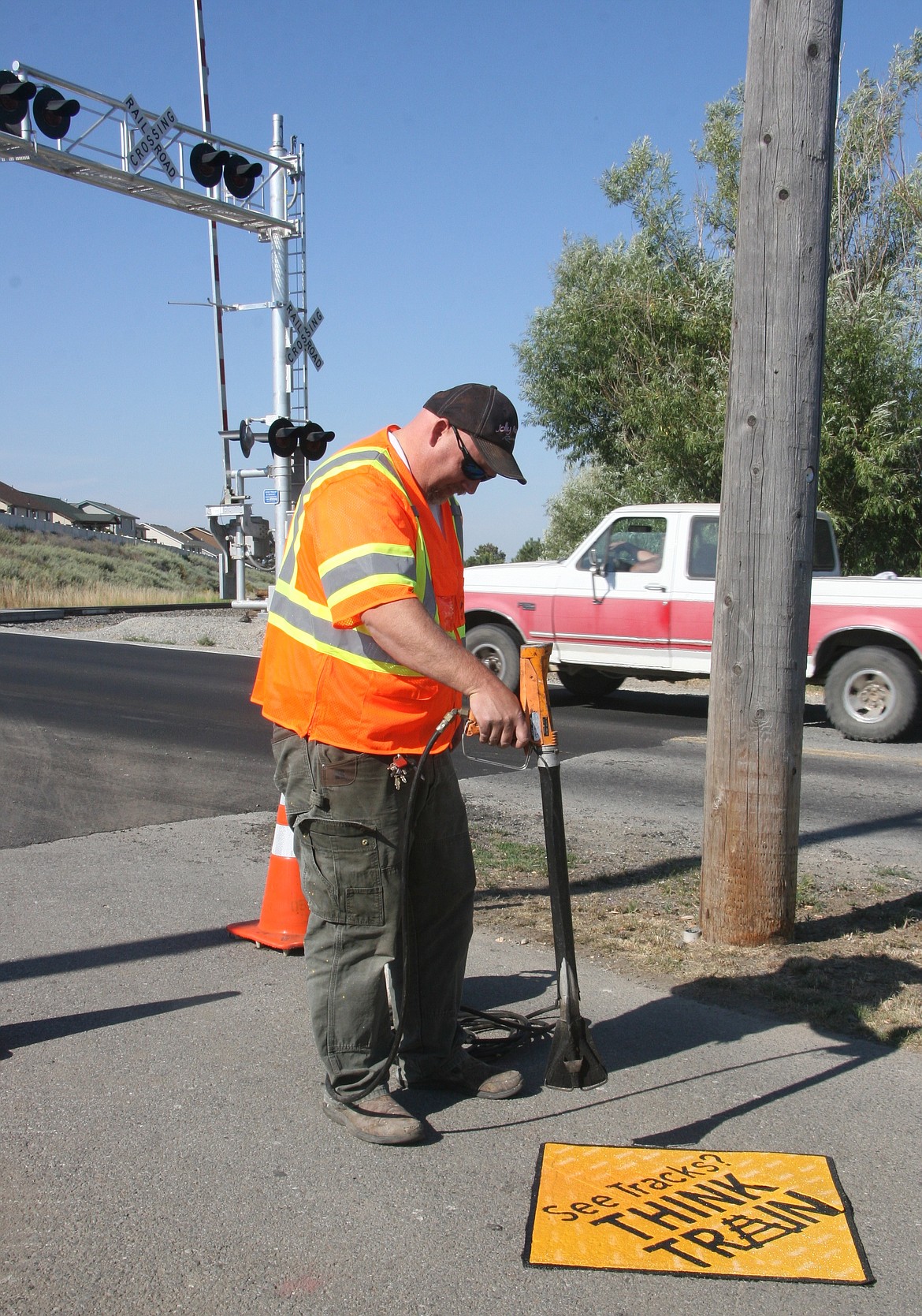 Jake Burkey of the Idaho Transportation Department heats a pedestrian warning decal on Wednesday at the Union Pacific Railroad crossing along Spokane Street in Post Falls. The decals are part of a pilot project at five locations statewide exploring low-cost ways of reducing accidents. (BRIAN WALKER/Press)