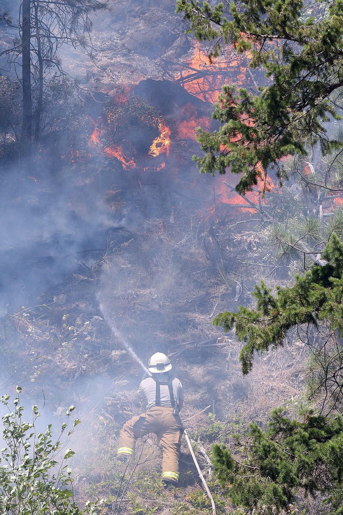 Libby volunteer firefighter Scott Beagle battles a blaze that broke out on the north side of Route 37 near the 4 mile marker Thursday afternoon. (John Blodgett/The Western News)