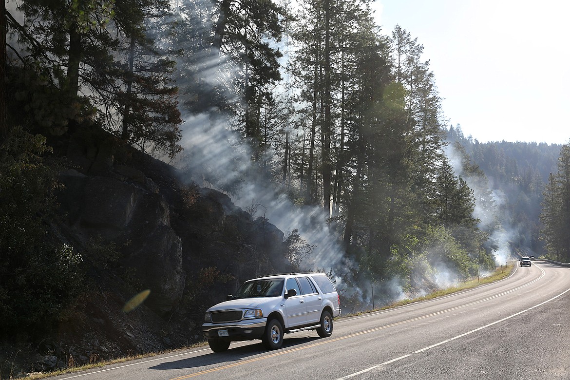 Traffic passes smoke from a burn-out operation on the Highway 37 fire Tuesday. (John Blodgett/The Western News)