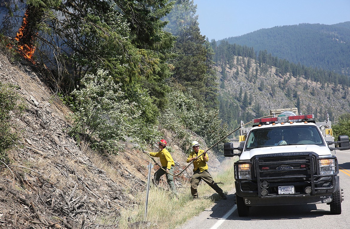 U.S. Forest Service firefighters prepare to extinguish a tree that flared up just north of milemarker 4 on Highway 37 Friday afternoon. The crew was in the area monitoring the slope where the Highway 37 fire began Thursday afternoon. (John Blodgett/The Western News)