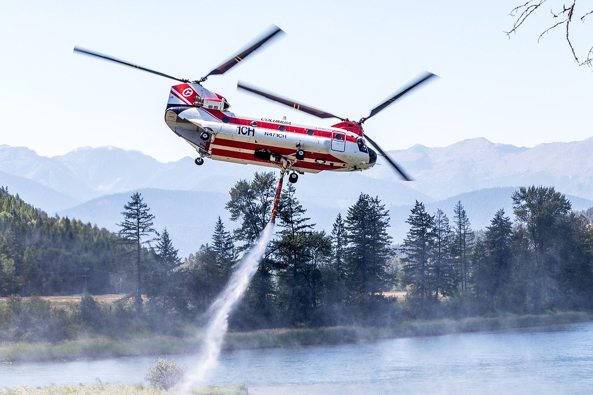 Filled with Kootenai River water, a Boeing CH-47 Chinook heads for the Highway 37 fire Saturday. (John Blodgett/The Western News)