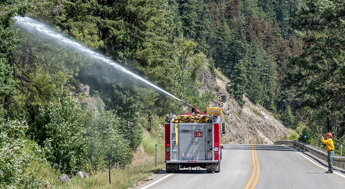 Steve Lauer, right, first assistant chief of Libby Volunteer Fire Department, directs firefighter Ryan Carpenter where to point the nozzle on a hot spot that flared up in the Highway 37 fire Saturday. (John Blodgett/The Western News)