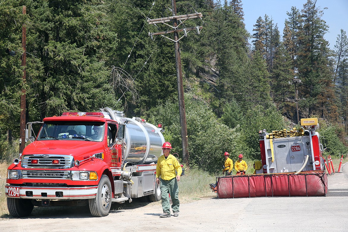 A Libby Volunteer Fire Department water tender and fire engine stand ready near milemarker 4 on Highway 37 Friday afternoon. (John Blodgett/The Western News)