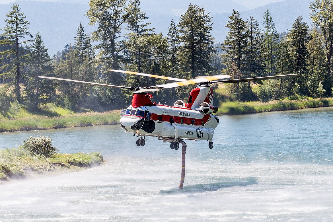 A Boeing CH-47 Chinook refills with Kootenai River water while fighting the Highway 37 fire Saturday. (John Blodgett/The Western News)