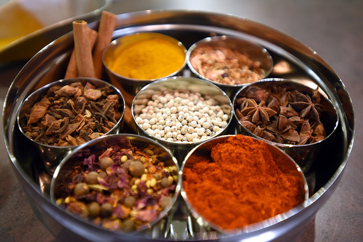 A collection of spices at World Spice Merchants. The spices are tumeric (the yellow spice at the top of the tray), around the right are fin and feather barbecue rub, star anise, Hungarian paprika, Ras El Hanout, Chinese five spice and in the center are white peppercorns.