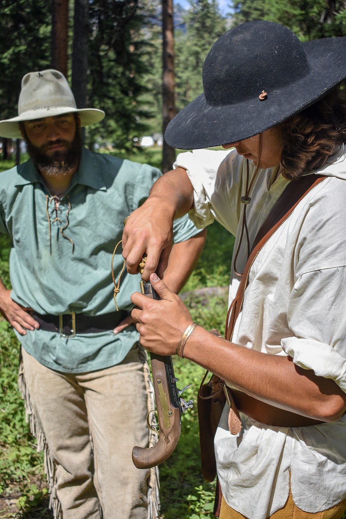 Trevor Horner loads powder into a pistol as Josh Snyder looks on during the Two Rivers Rendezvous near Libby July 14. (Ben Kibbey/ The Western News)