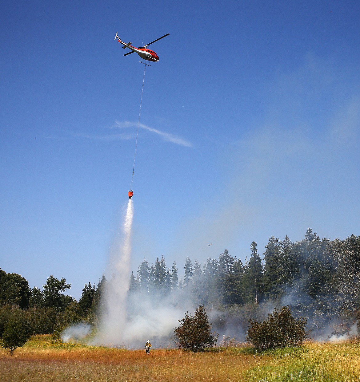 A helicopter dumps water on a fire at Dodd and Strahorn roads in Hayden. There were around at least six different wildfires, possibly more, burning in various locations throughout the north and western sections of Kootenai County on Monday. (LOREN BENOIT/Press)