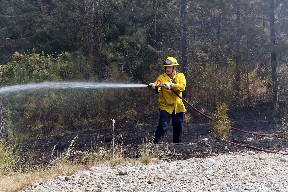 David Sherman of the Northern Lakes Fire District mops up a wildfire near the Avondale electrical substation at Lancaster Rd. and U.S. Highway 95 in Hayden on Monday. (JUDD WILSON/Press)