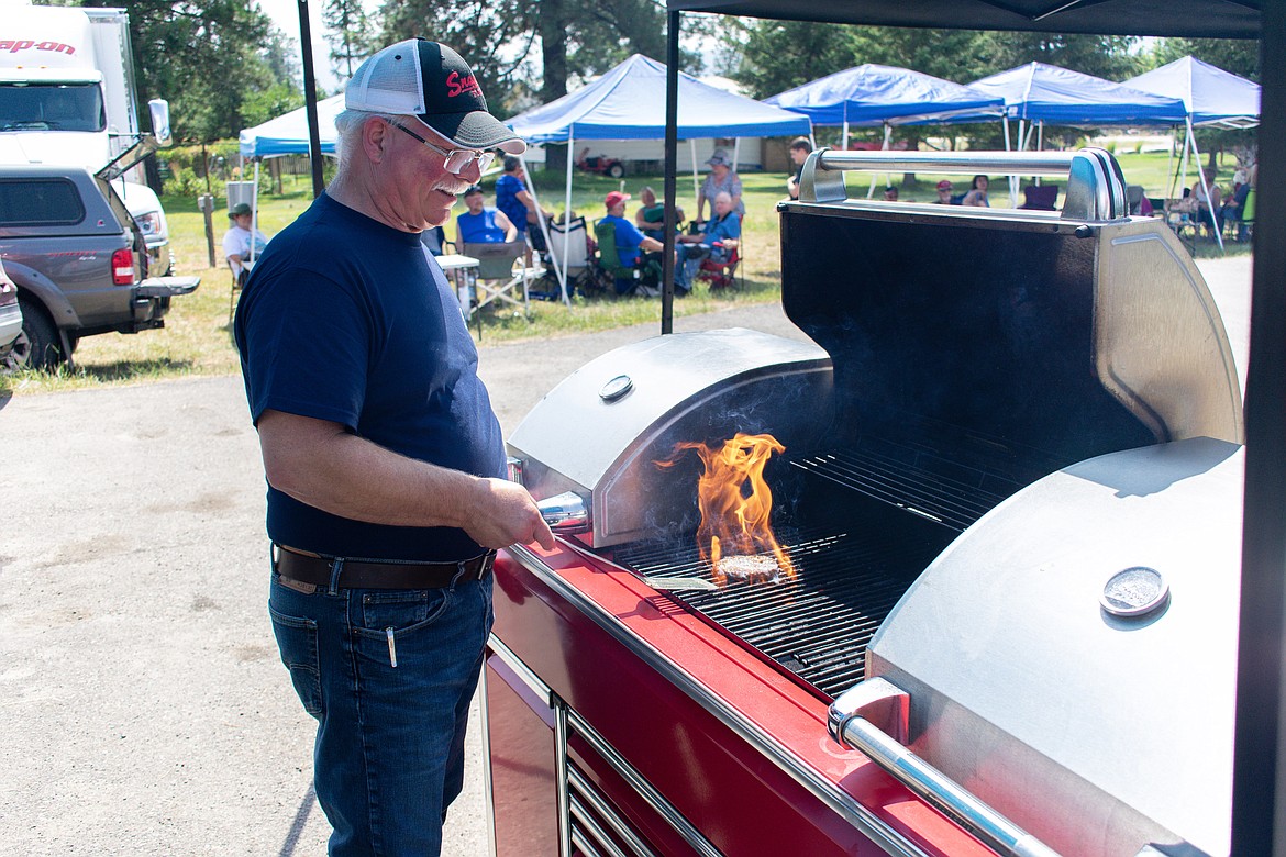 Snap-On franchisee Dean Peasley flips burgers on his grill built to resemble a tool cabinet Saturday during the RMV Auto Car Show south of Libby. Peasley said he likes to give back to the community in Libby out of gratitude for the business they give him. (Ben Kibbey/The Western News)