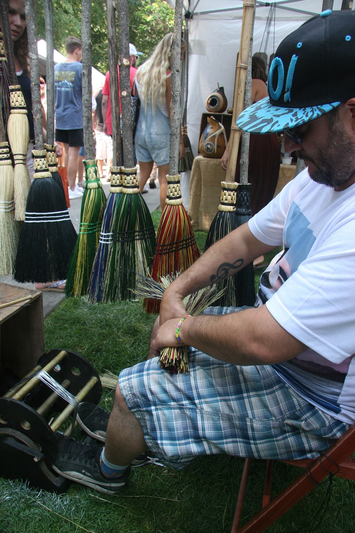 Michael Page, an owner of Backwoods Broom in Eugene, Ore., winds a broom made of died sorghum plants on Saturday at Coeur d&#146;Alene City Park. (BRIAN WALKER/Press)