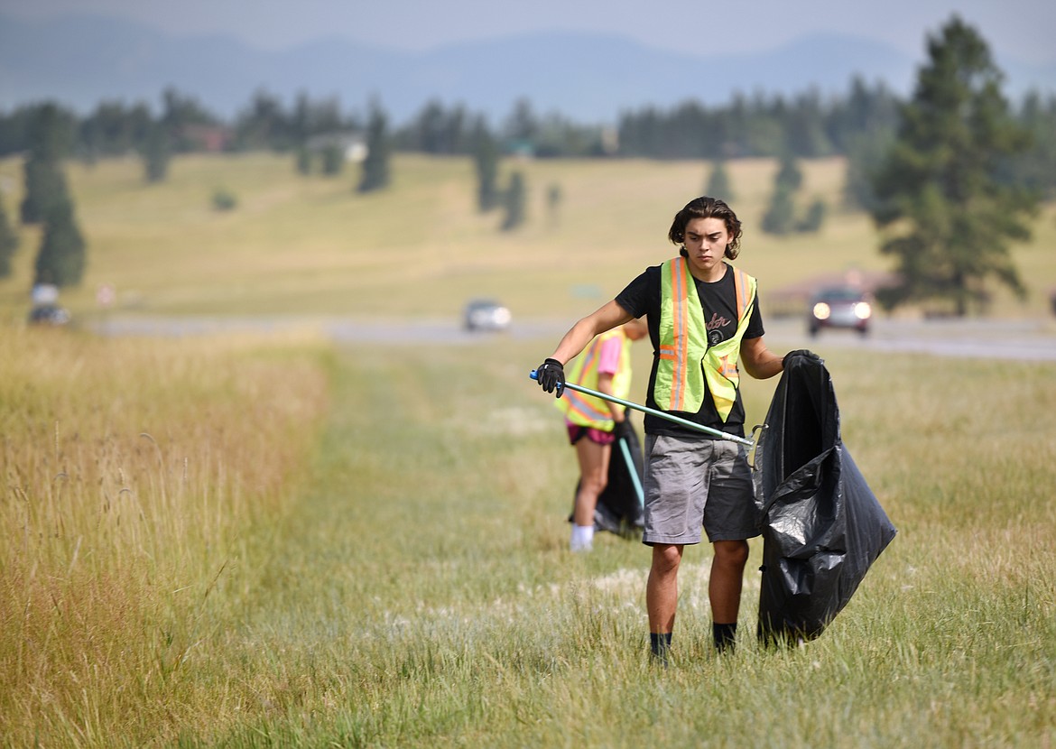 Rylin Madsen, 18, picks up trash along U.S. 93 north of Kalispell on Tuesday, August 7. In the background is fellow summer employee of Flathead County Parks and Recreation.(Brenda Ahearn/Daily Inter Lake)